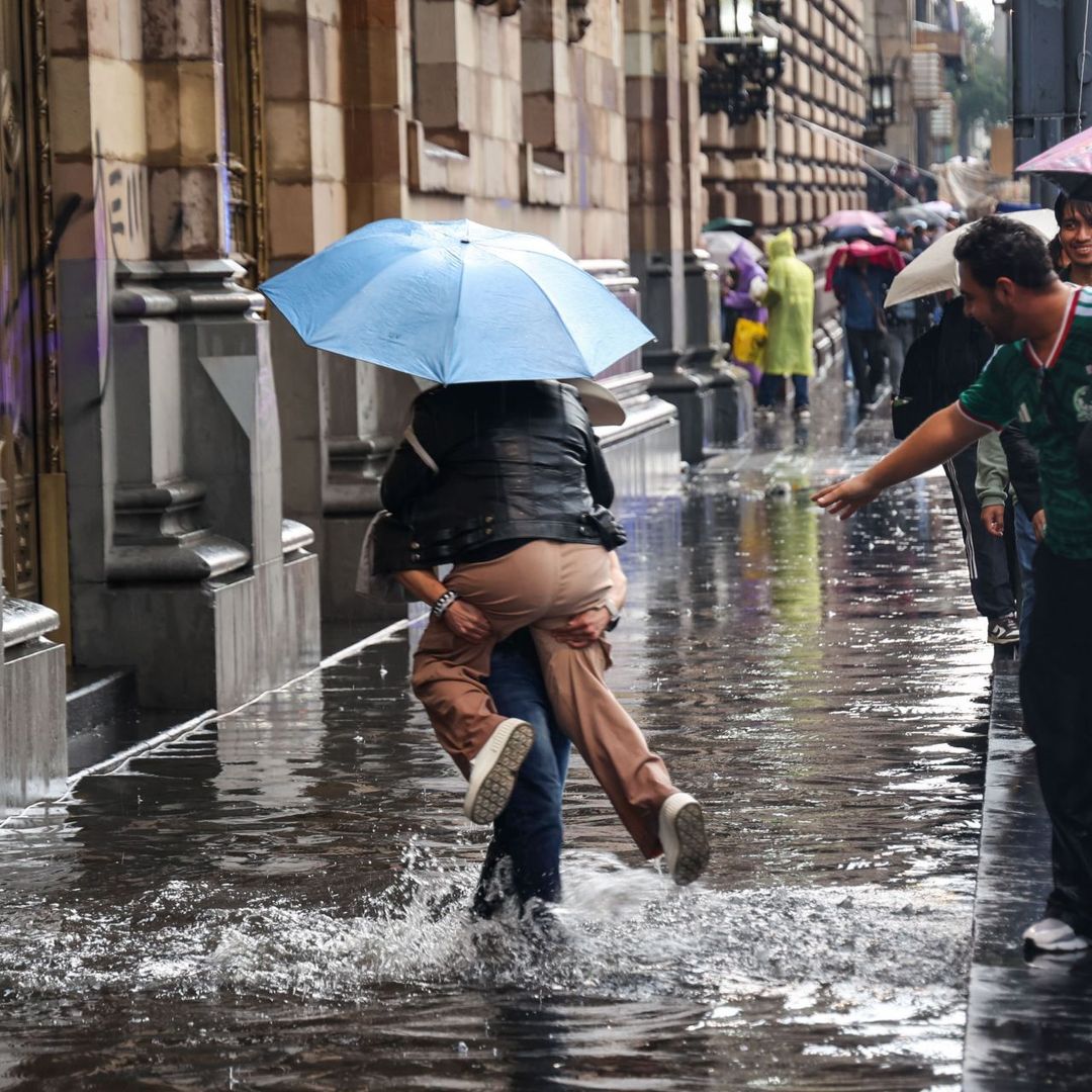 Un hombre ayuda a cruzar un encharcamiento a una joven que se había quedado atrapada. Foto: Cuartoscuro